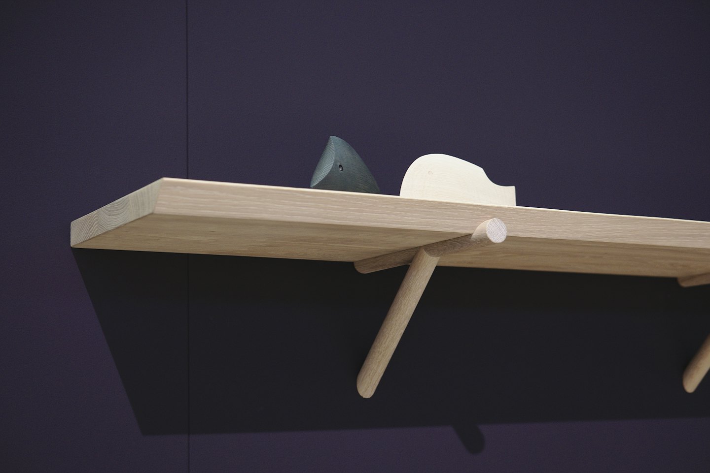 Two minimalist wooden ornaments sit on a light oak shelf.