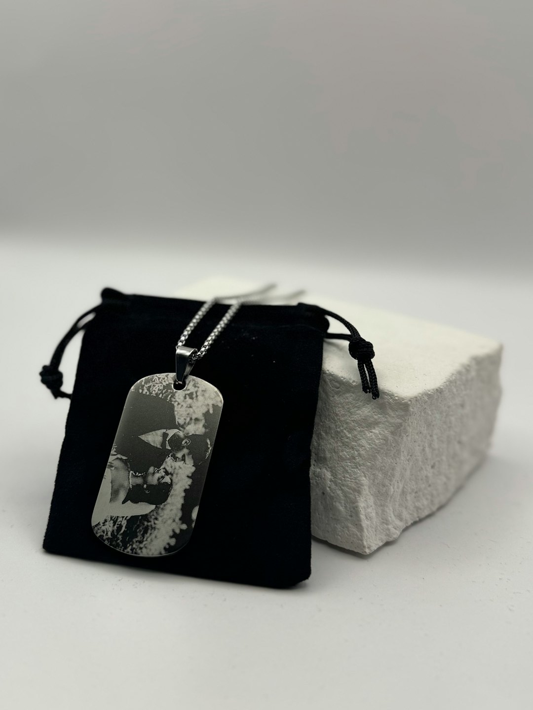 Personalized dog tag pendant on a silver chain in a pouch.
